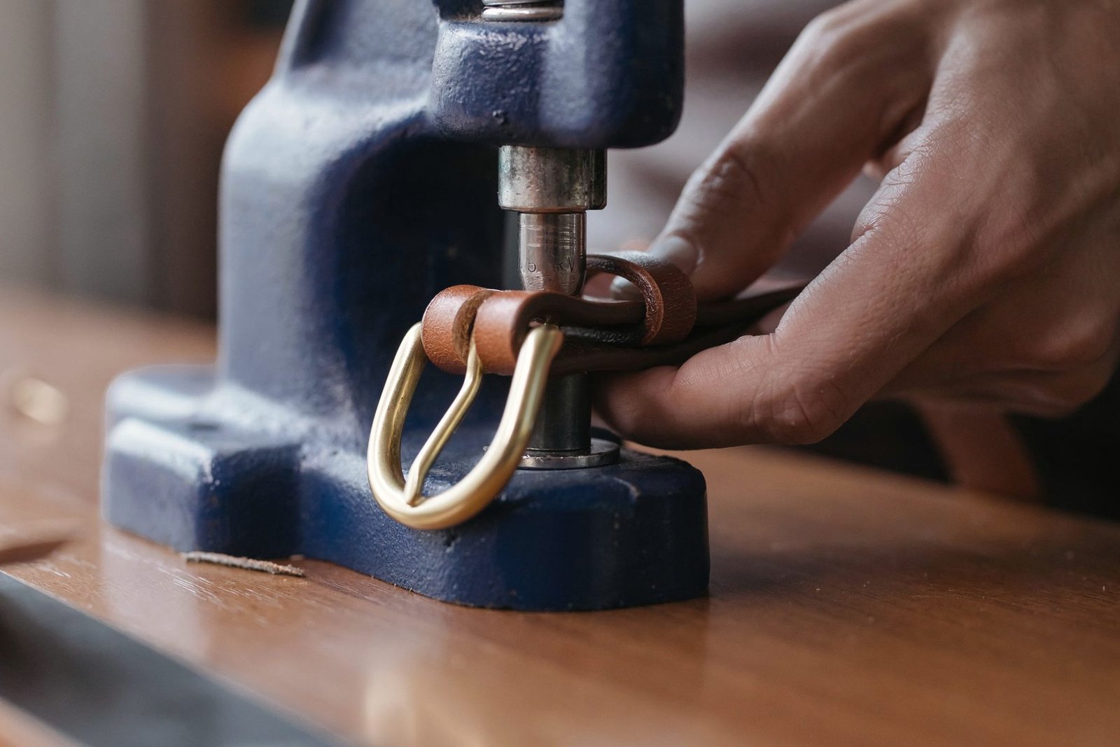 Hardware being set into a strap under a hand press.