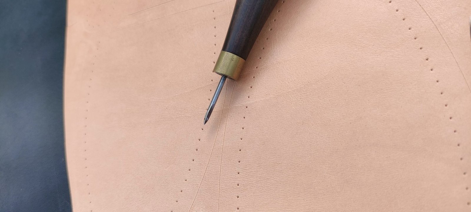 A scribe marking a stitch line along a leather edge.